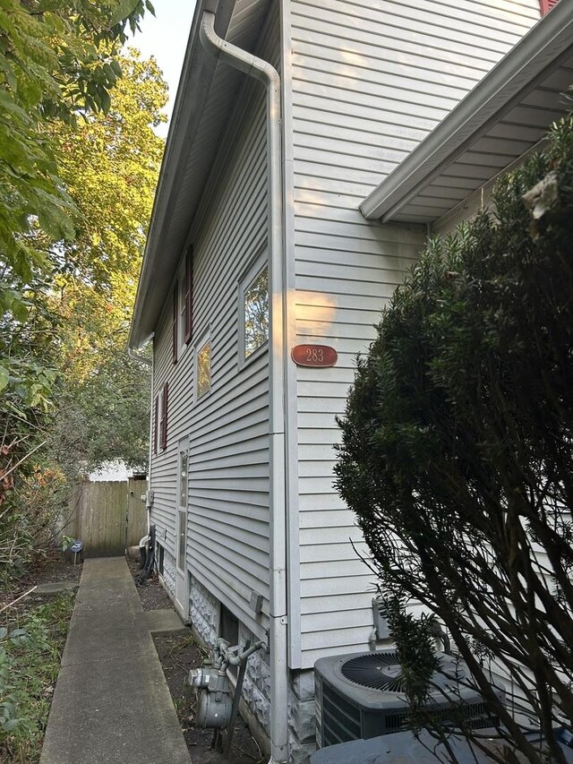 view of side of home with central AC and fence