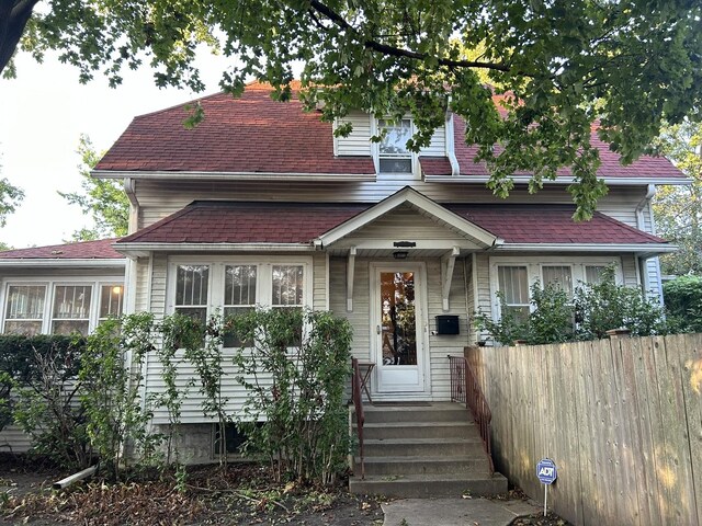 view of front facade featuring fence and roof with shingles