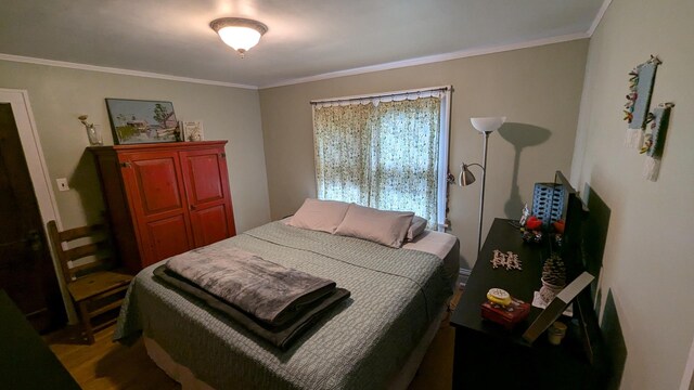 bedroom featuring ornamental molding and wood finished floors