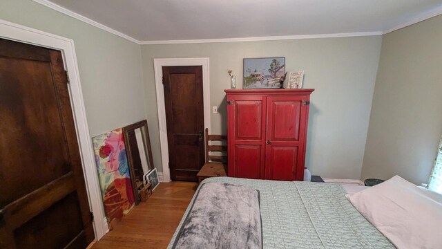 bedroom featuring crown molding and light wood-style flooring