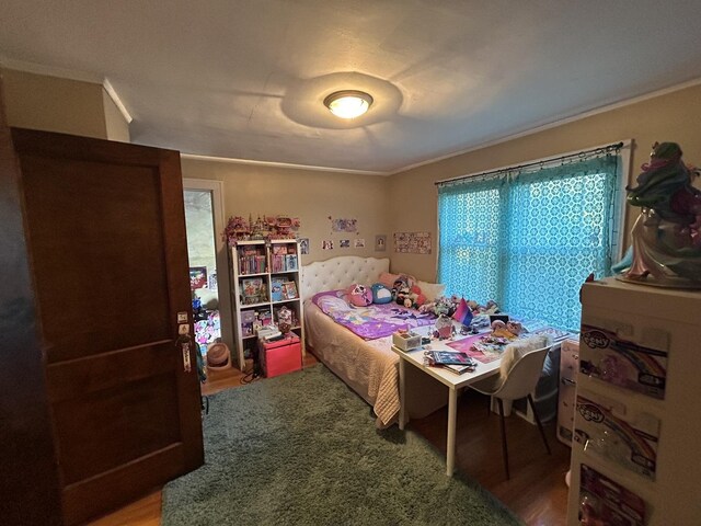 bedroom featuring ornamental molding and wood finished floors