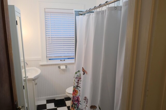 bathroom featuring a shower with curtain, wainscoting, vanity, tile patterned floors, and toilet