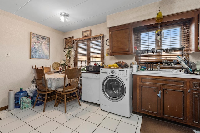 clothes washing area with laundry area, light tile patterned flooring, washer / clothes dryer, and a wealth of natural light