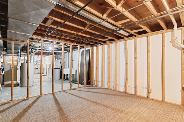unfinished below grade area with water heater, carpet floors, washer / dryer, and a sink