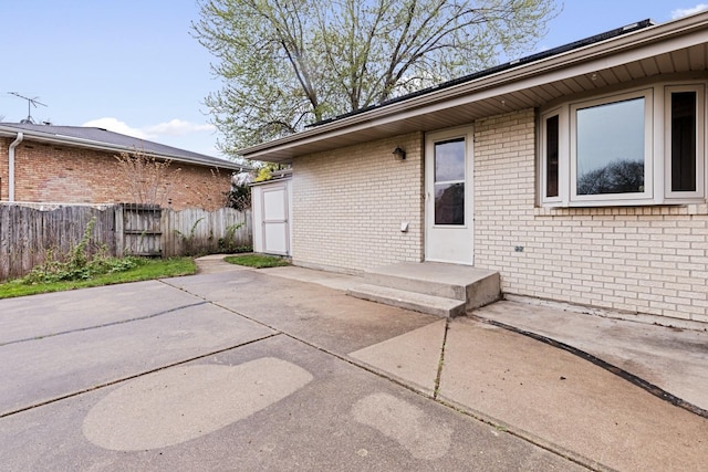 exterior space with brick siding, fence, and a patio area