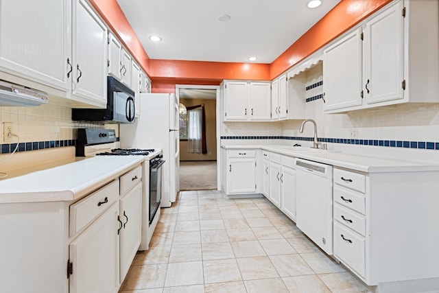 kitchen with white dishwasher, black microwave, a sink, backsplash, and gas range oven