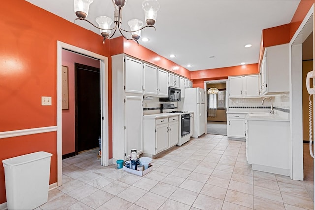 kitchen featuring white appliances, light countertops, a chandelier, white cabinets, and a sink
