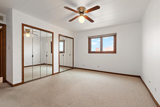 unfurnished bedroom featuring baseboards, light carpet, two closets, and a ceiling fan