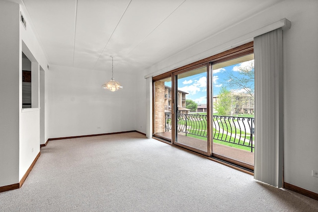 carpeted spare room featuring baseboards, a notable chandelier, and visible vents
