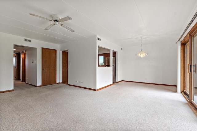 spare room with visible vents, baseboards, ceiling fan with notable chandelier, and light carpet