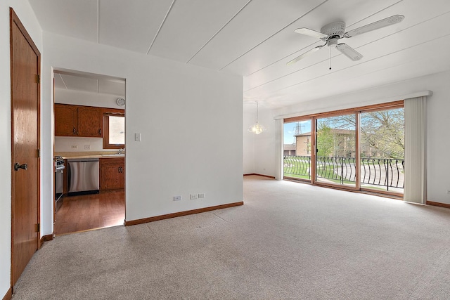 spare room featuring a sink, baseboards, a ceiling fan, and light colored carpet