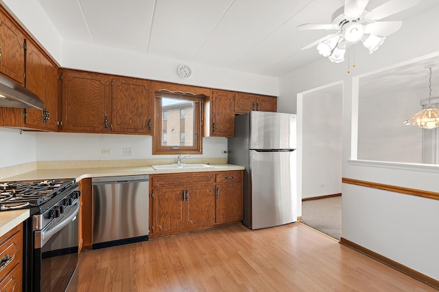 kitchen with light wood-style floors, a sink, brown cabinets, and stainless steel appliances