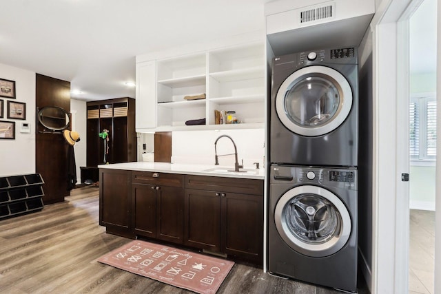 washroom with stacked washer / dryer and wood finished floors