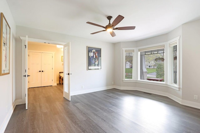 spare room featuring dark wood finished floors, a ceiling fan, and baseboards