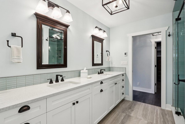 bathroom featuring double vanity, a tile shower, decorative backsplash, and baseboards