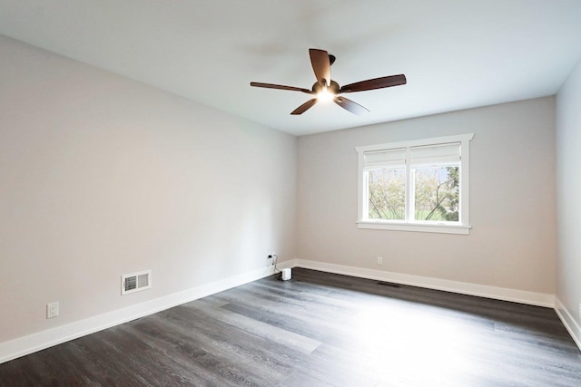 spare room featuring baseboards, ceiling fan, and dark wood finished floors