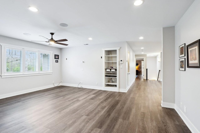 spare room with a ceiling fan, wood finished floors, recessed lighting, baseboards, and built in shelves