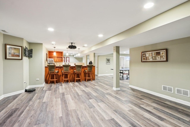 living room with light wood-type flooring, baseboards, recessed lighting, and bar area