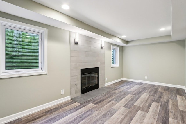 unfurnished living room with wood finished floors, a fireplace, baseboards, and recessed lighting