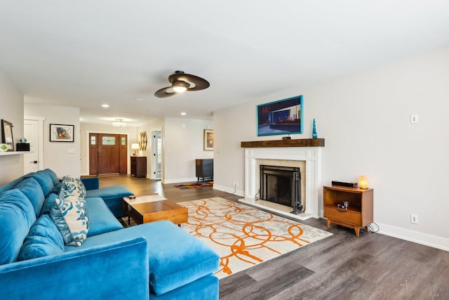 living room with wood finished floors, a fireplace with raised hearth, baseboards, and recessed lighting