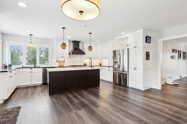 kitchen featuring appliances with stainless steel finishes, wall chimney range hood, recessed lighting, dark wood-style floors, and a sink
