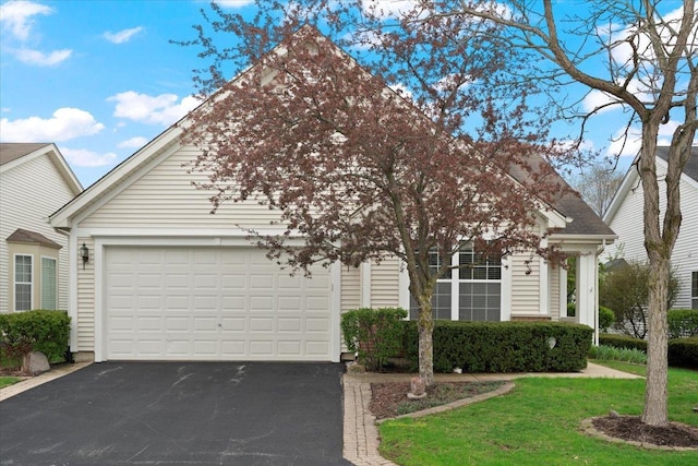 view of front of home with an attached garage, a front lawn, and aphalt driveway