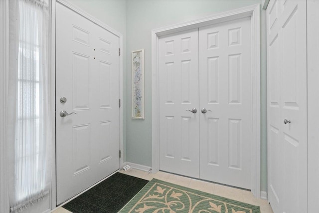 foyer entrance with light tile patterned flooring and baseboards