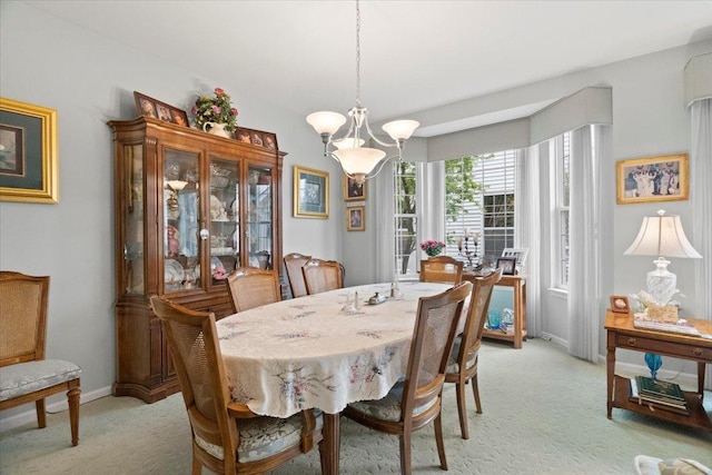 dining area featuring light colored carpet, baseboards, and an inviting chandelier