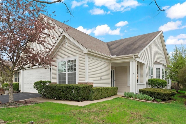 view of front facade featuring a shingled roof, an attached garage, driveway, and a front yard