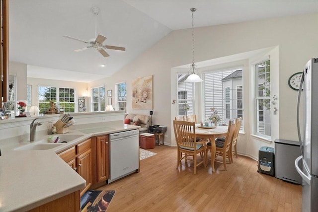 kitchen featuring freestanding refrigerator, white dishwasher, light countertops, light wood-style flooring, and vaulted ceiling