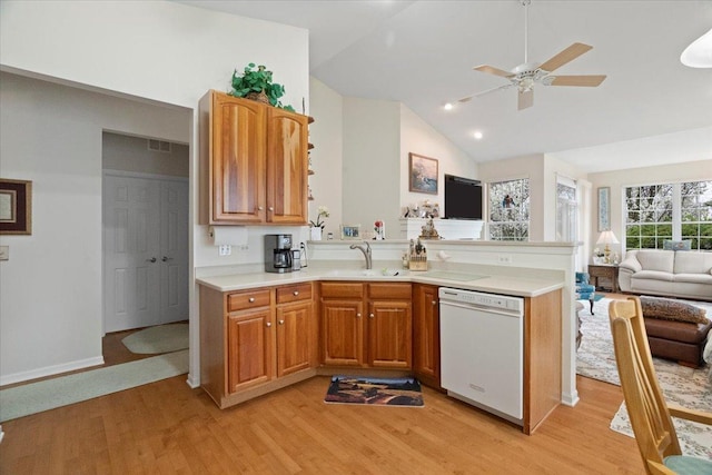 kitchen featuring a sink, light wood finished floors, a peninsula, and dishwasher