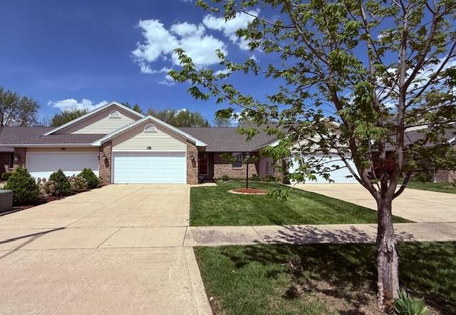 ranch-style home with an attached garage, concrete driveway, brick siding, and a front yard