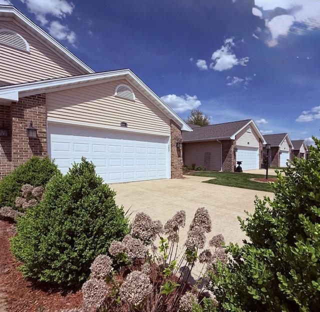 view of property exterior with concrete driveway, brick siding, and an attached garage