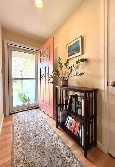 doorway featuring baseboards and light wood finished floors