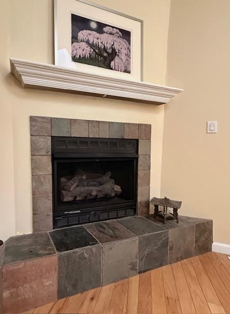 interior details with baseboards and a tiled fireplace