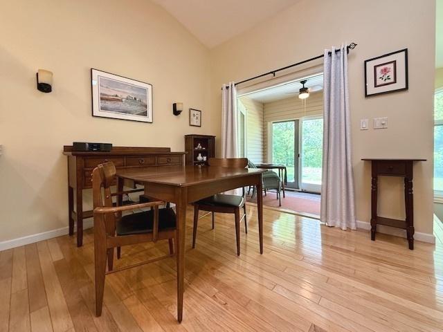 dining room featuring baseboards, light wood-style flooring, and vaulted ceiling