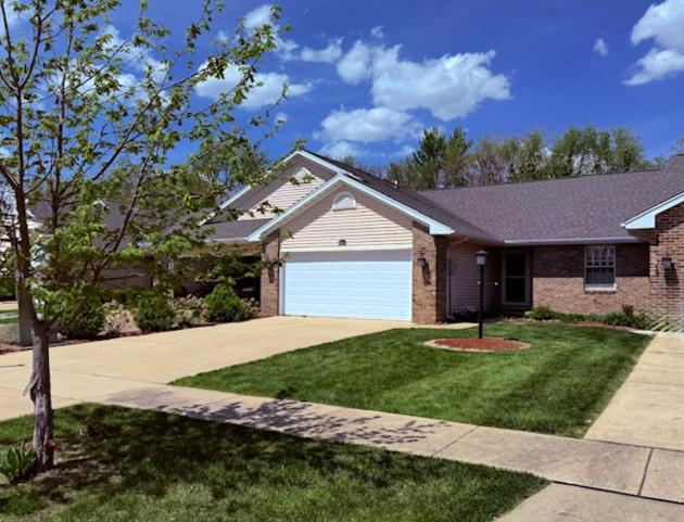single story home with brick siding, a garage, a front yard, and concrete driveway