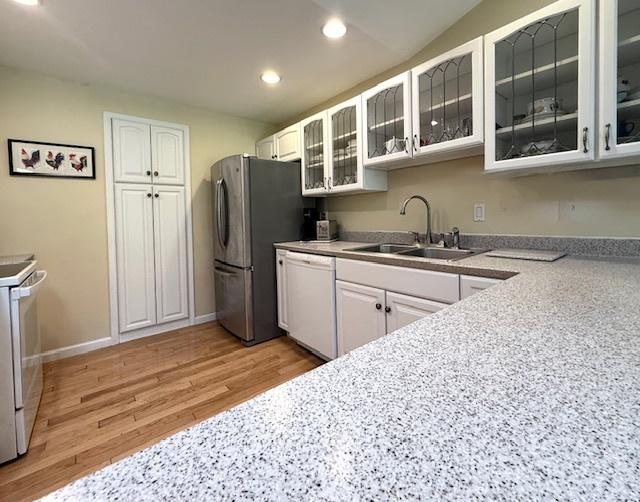 kitchen with recessed lighting, a sink, white cabinets, and white appliances