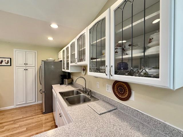 kitchen with dishwasher, a sink, white cabinets, glass insert cabinets, and recessed lighting