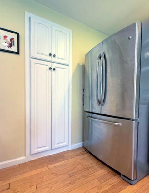 kitchen with freestanding refrigerator, white cabinetry, baseboards, and light wood-type flooring