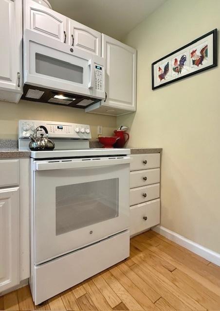 kitchen featuring light wood finished floors, white appliances, and white cabinetry