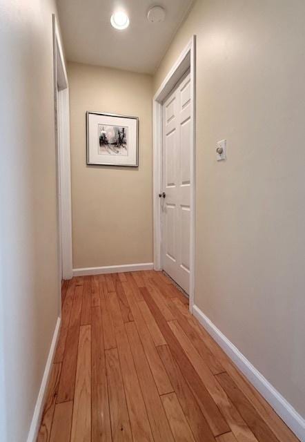corridor featuring light wood-type flooring and baseboards