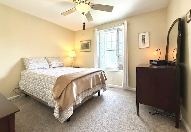 carpeted bedroom with ceiling fan and baseboards