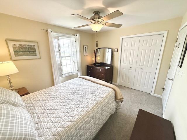 bedroom with a ceiling fan, baseboards, carpet, and a closet
