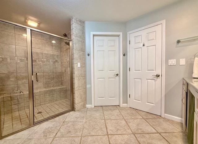 full bath featuring tile patterned floors, baseboards, and a stall shower