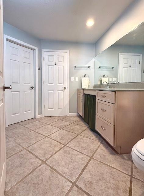 bathroom featuring toilet, tile patterned floors, baseboards, and vanity