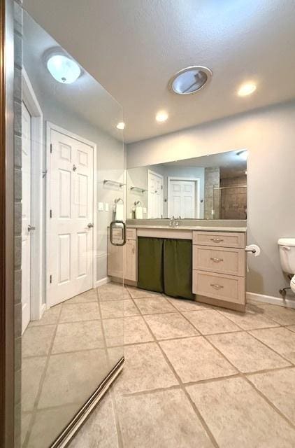 bathroom featuring tile patterned flooring, vanity, a shower, toilet, and baseboards