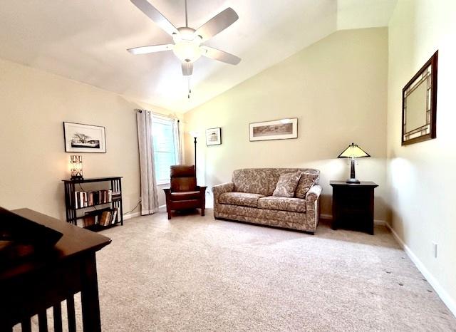 living area with baseboards, ceiling fan, carpet, and vaulted ceiling