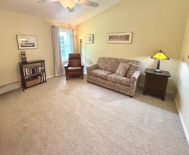 living area with carpet floors, a ceiling fan, baseboards, and vaulted ceiling