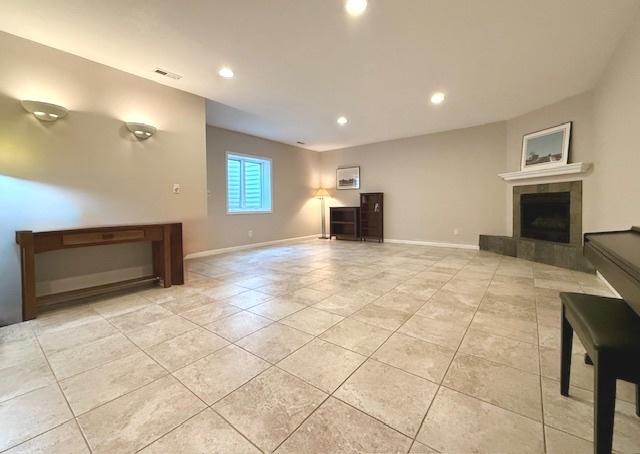 unfurnished living room with light tile patterned floors, baseboards, a tiled fireplace, and recessed lighting